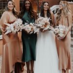 3 women in satin bridesmaid dresses in several colors and a bride
