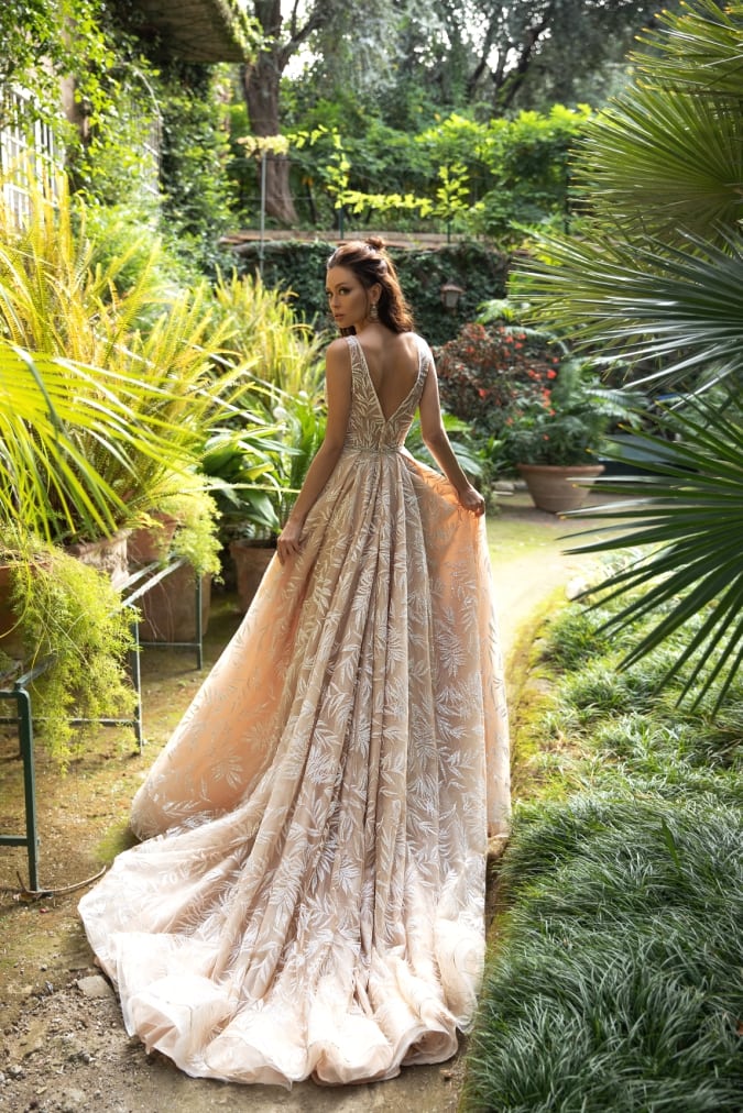 Neutral lace wedding dress shown against a garden