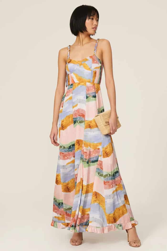 Multicolored maxi dress with spaghetti straps shown on a model holding a clutch