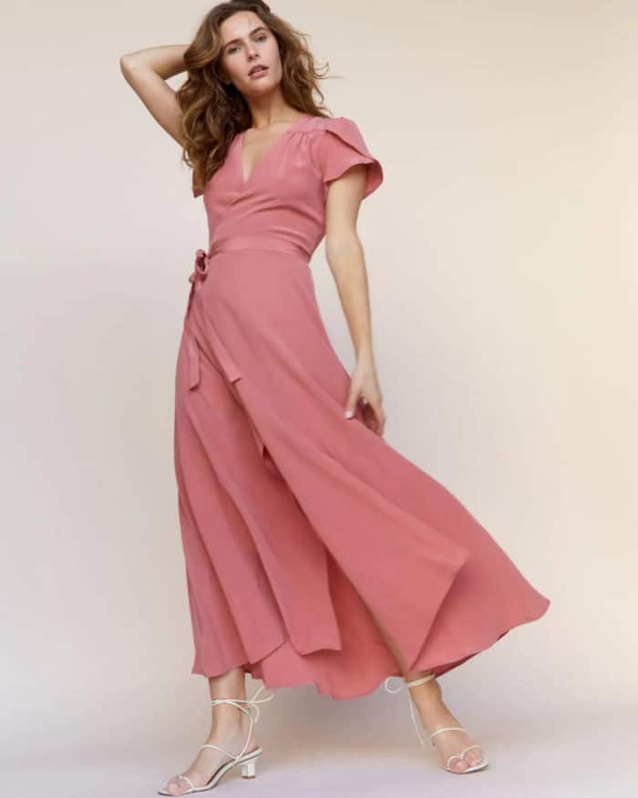 Pink wrap maxi dress with short sleeves made by a fair trade clothing company, shown on a model twirling