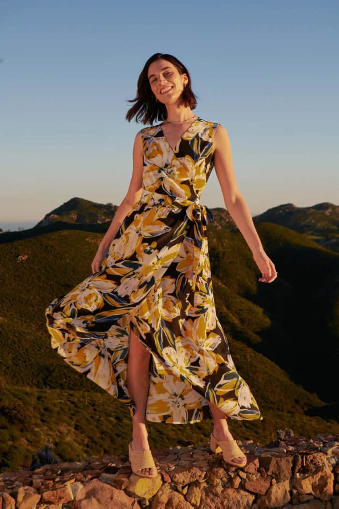 Eco-conscious floral silk maxi dress with navy blue background and gold floral print shown on a model
