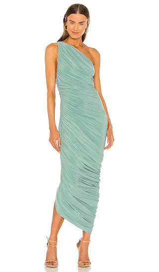 Model wearing a one shoulder midi length cocktail dress in a sage green color