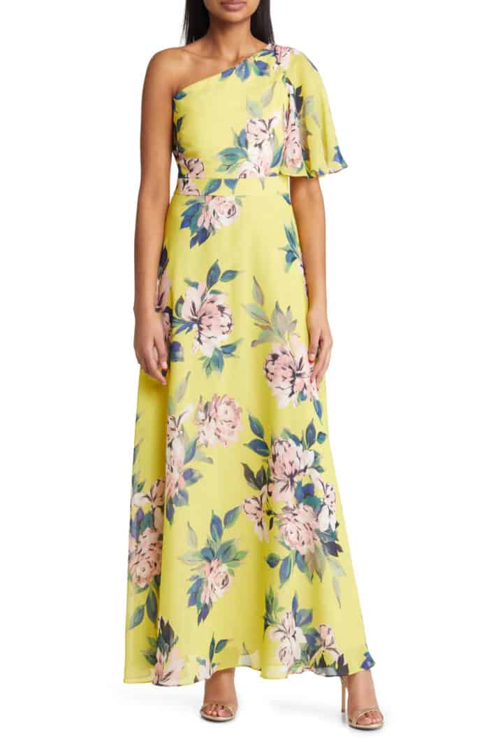 Yellow one shoulder gown with pink and green floral accents shown on a model