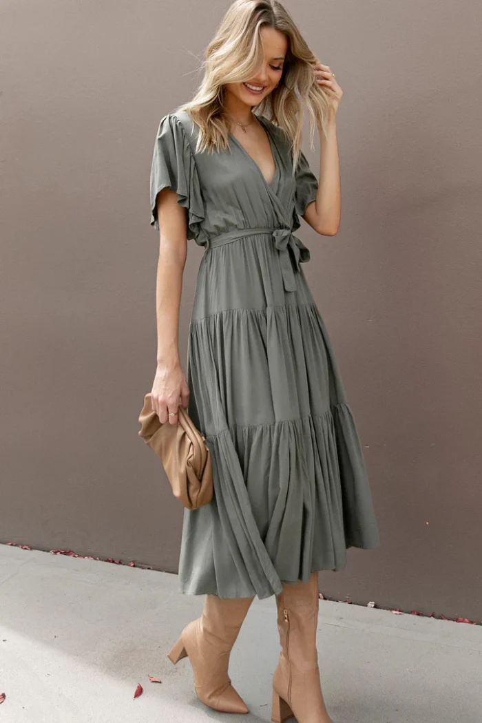 Product image showing model wearing an olive green midi dress with short flutter sleeves and tierd skirt