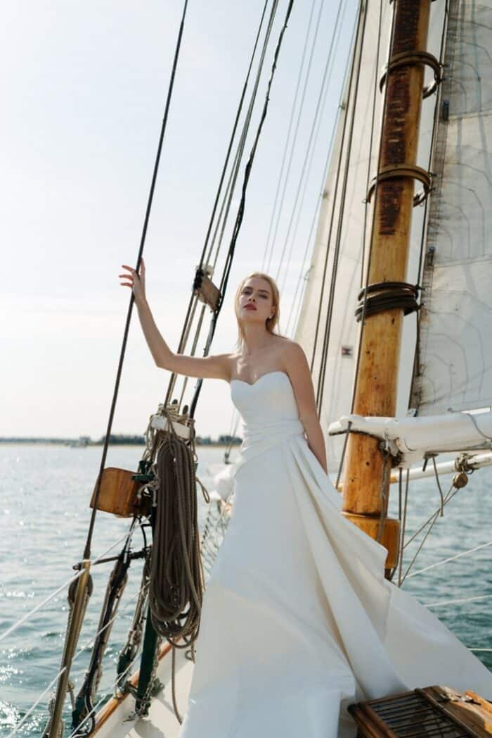 Model wearing strapless ivory wedding dress on a historic sailboat in Nantucket