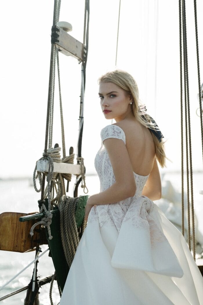 Model wearing cap sleeve wedding dress on sailboat