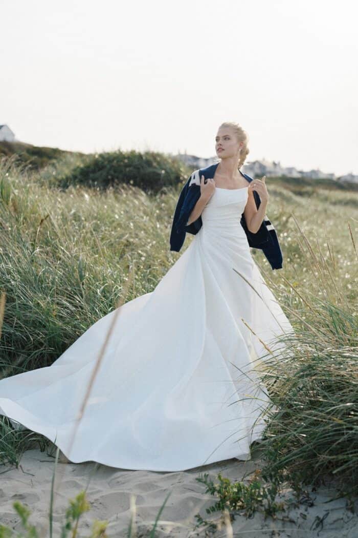 Model wearing strapless wedding dress with long train in the dunes of Nantucket