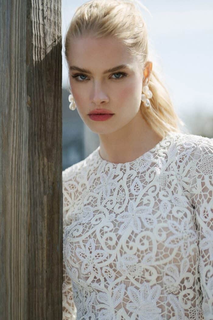 Close up image of model wearing a short lace wedding dress