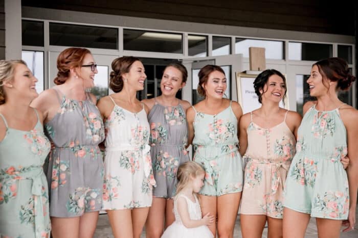 Group of bridesmaids wearing pastel floral rompers in shades of gray, pink and mint green