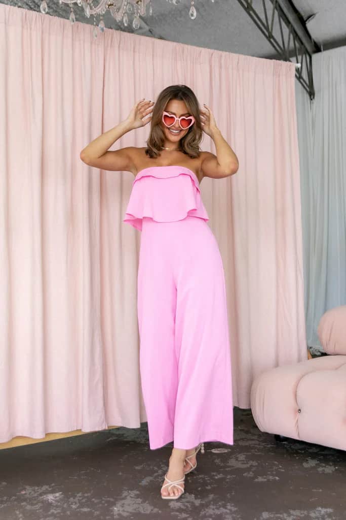 Bright pink strapless jumpsuit on model.