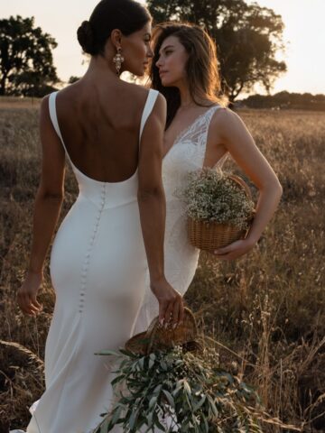 Two models wearing wedding dresses in an outdoor sunset.