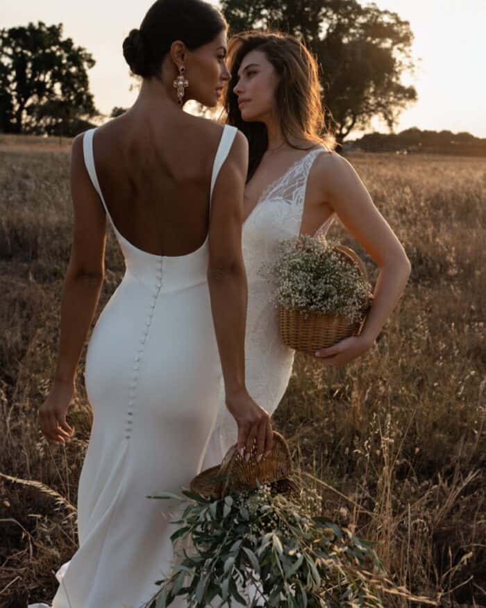 Two models wearing wedding dresses in an outdoor sunset.