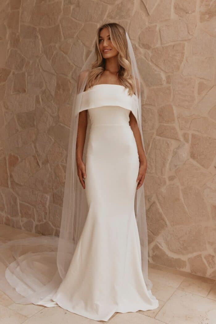 model wears an off the shoulder long ivory wedding dress