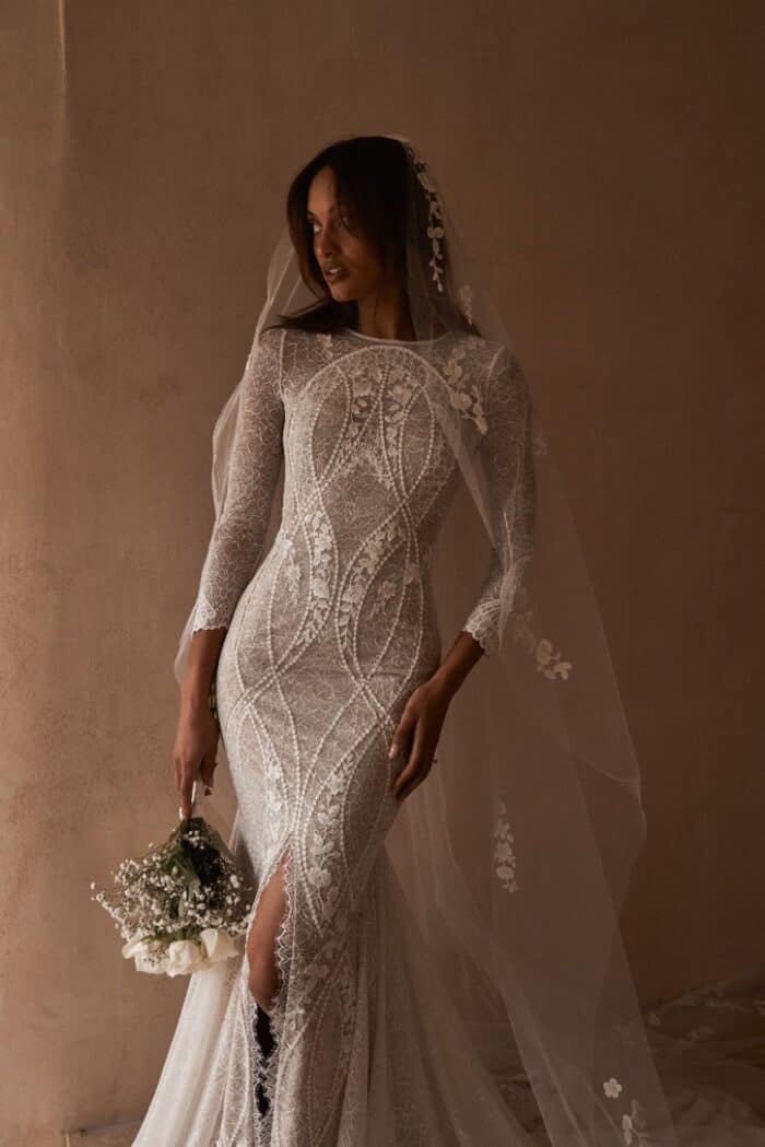 Model wearing long sleeve fitted lace wedding dress.